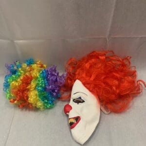 A clown mask and wig are on the floor.