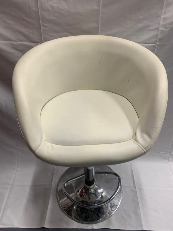 A white chair with a chrome base and a round seat.