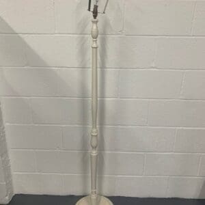 A white metal floor lamp with a round base.