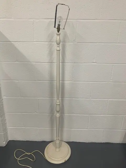 A white metal floor lamp with a round base.