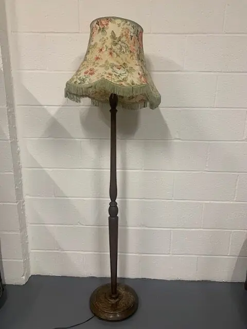 A lamp is on the floor in front of a wall.