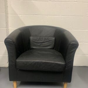 A black leather chair in front of a white wall.