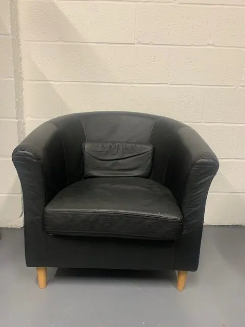 A black leather chair in front of a white wall.