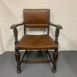 A wooden chair with brown leather seat and back.