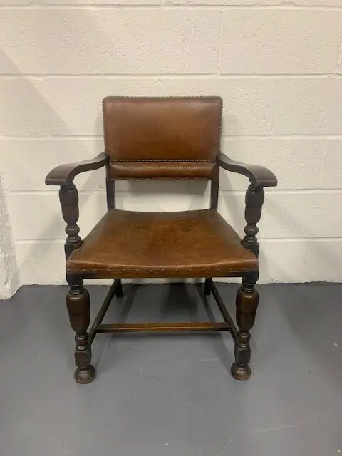 A wooden chair with brown leather seat and back.