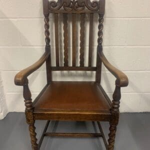 A wooden chair with a carved back and arms.