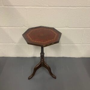 A small table with leather top and wooden base.