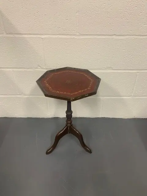 A small table with leather top and wooden base.