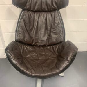 A brown leather chair sitting in front of a white wall.