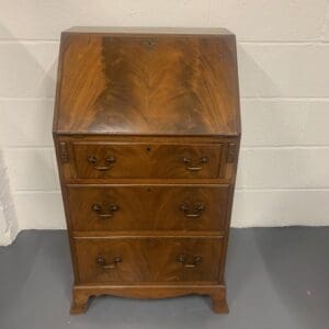 A wooden desk with three drawers and two doors.