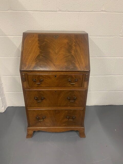 A wooden desk with three drawers and two doors.