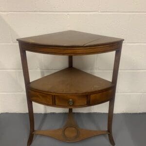 A corner table with one drawer and two shelves.