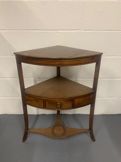 A corner table with one drawer and two shelves.