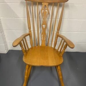 A wooden rocking chair sitting in front of a white wall.