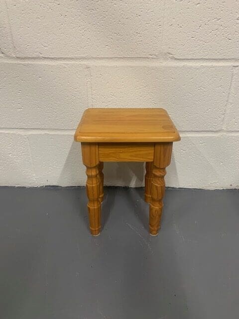 A small wooden table sitting in front of a wall.