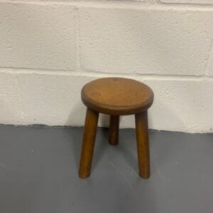 A small wooden stool sitting on the ground.