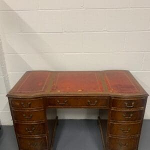 A desk with leather top and drawers.