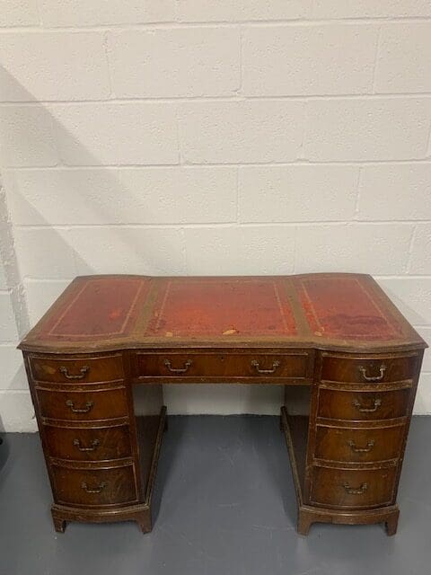 A desk with leather top and drawers.