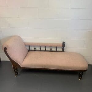 A wooden chaise lounge chair with beige upholstery.