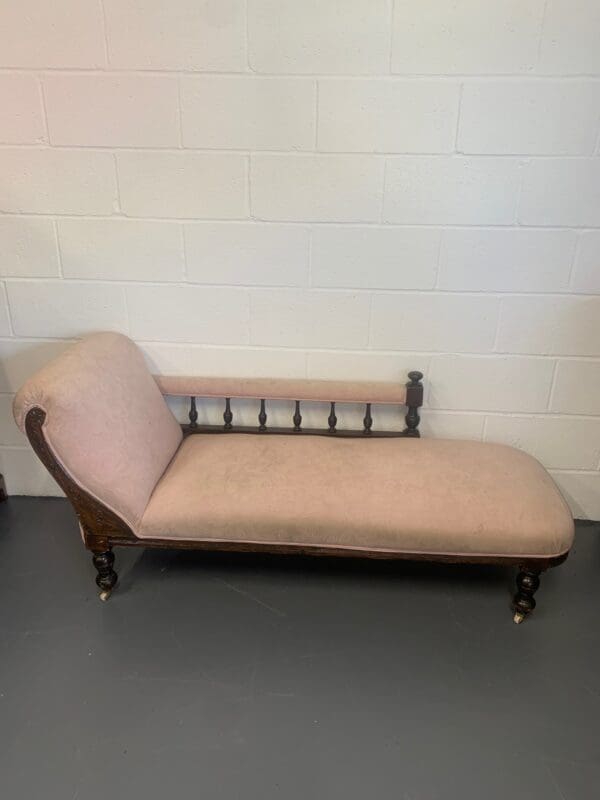 A wooden chaise lounge chair with beige upholstery.