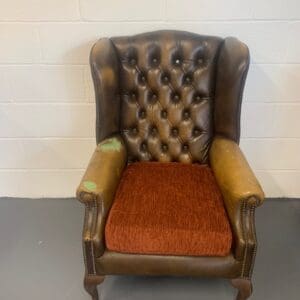 A brown leather chair with red seat cushion.