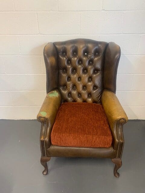 A brown leather chair with red seat cushion.