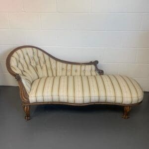 A chaise lounge chair with striped fabric.