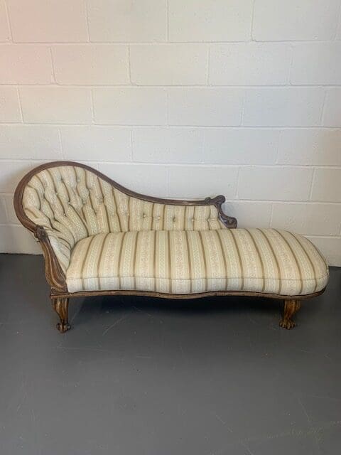 A chaise lounge chair with striped fabric.