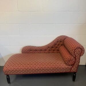 A red and black chaise lounge chair in front of a white wall.