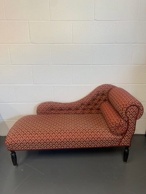 A red and black chaise lounge chair in front of a white wall.