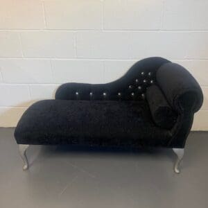 A black chaise lounge chair with silver legs.