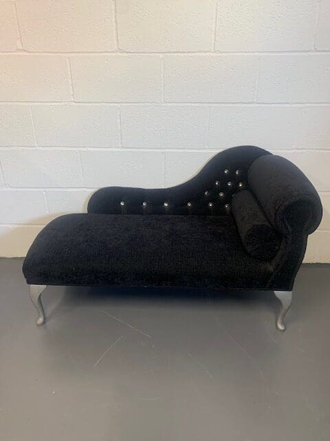 A black chaise lounge chair with silver legs.