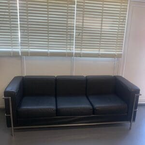 A black couch sitting in front of a window.