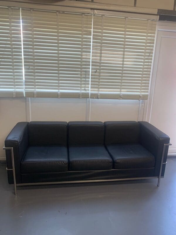 A black couch sitting in front of a window.