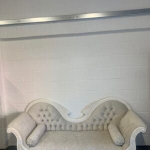 A white couch with two pillows on it.