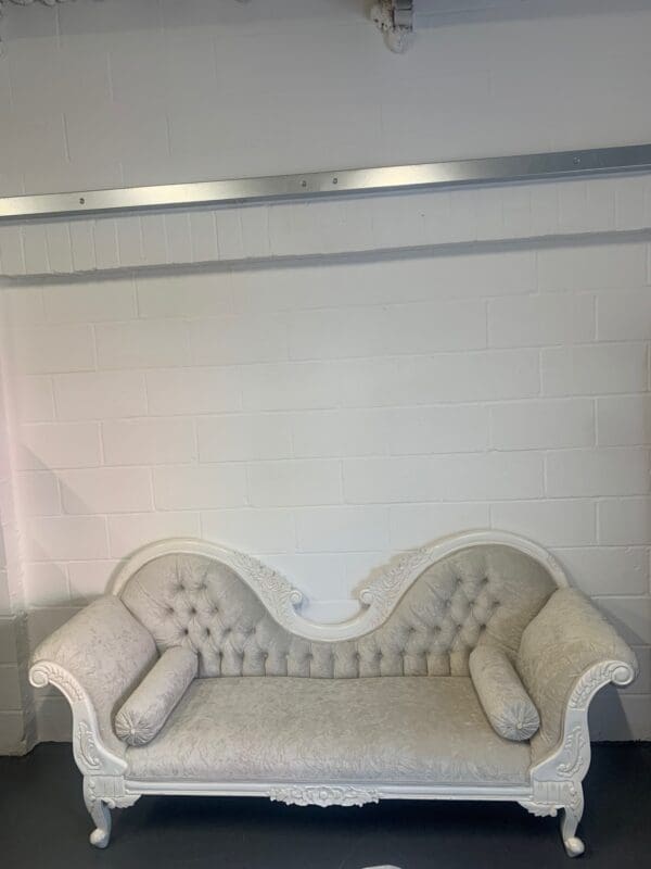 A white couch with two pillows on it.