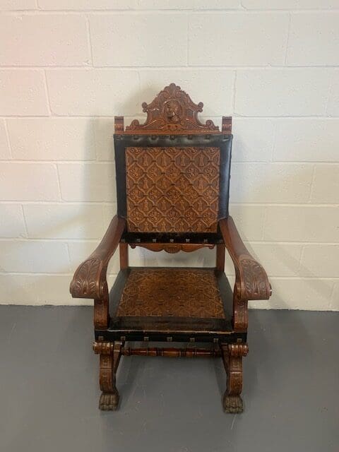 A wooden chair with a black leather seat.