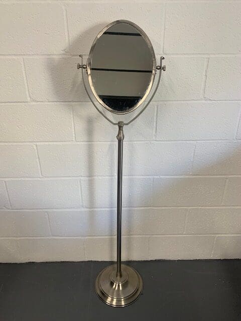 A mirror that is on the floor in front of a wall.