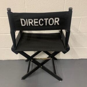 A black director chair sitting in front of a wall.