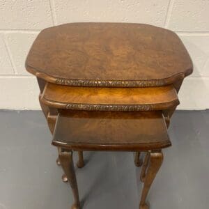 A set of three wooden tables with one smaller table on the other.