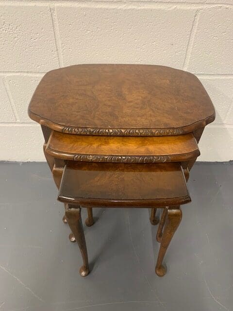 A set of three wooden tables with one smaller table on the other.