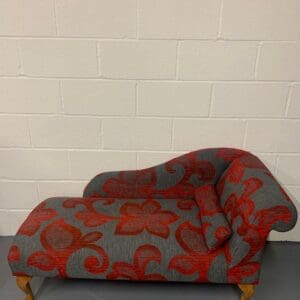 A red and grey couch with a white wall behind it.