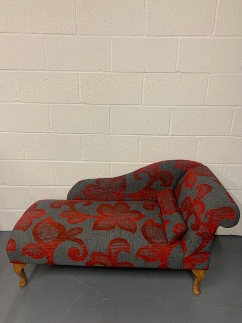 A red and grey couch with a white wall behind it.