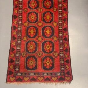 A red rug with yellow and black designs on it.