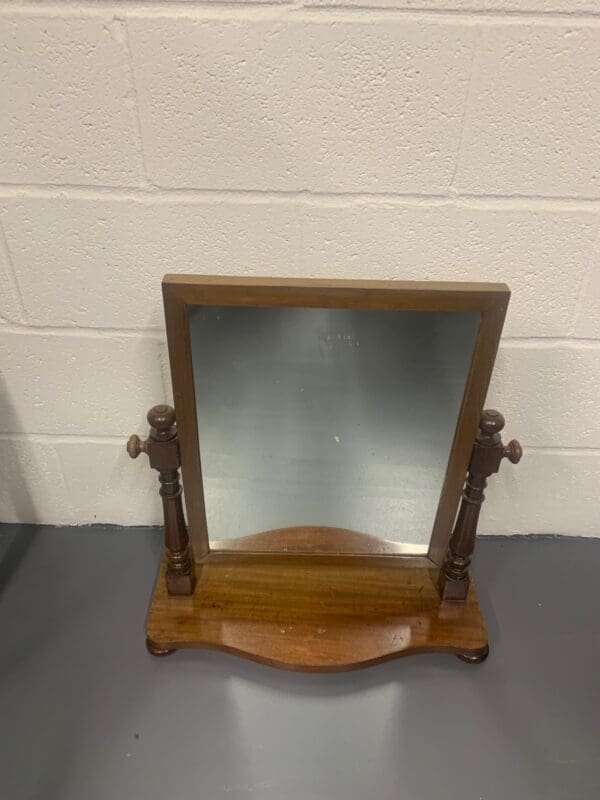 A wooden mirror sitting on top of a table.