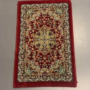 A red rug with a floral design on it.