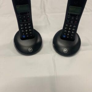 A pair of black cordless phones on top of a table.