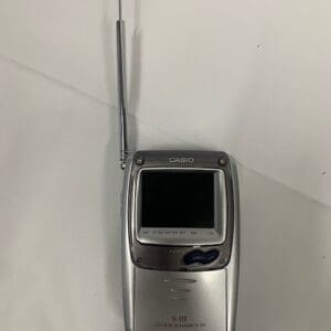 A silver flip phone sitting on top of a wall.