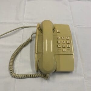 A beige telephone sitting on top of a white table.