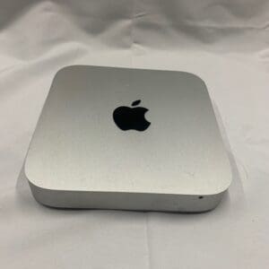 A silver apple mac mini sitting on top of a white table.